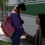 Still from the film "For Angela" featuring Angela Saskosky and her mother, Rhonda Gordon, outside of a bus. Angela, a young Indigenous girl, is hanging her head and her mother, an Indigenous woman in her thirties, is on her knees talking to her.