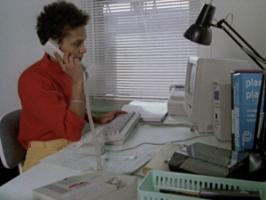 Still from the film "The Glass Ceiling" featuring one of the subjects, a young black woman, working as a receptionist.