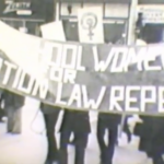 Still from "Women in Struggle" featuring blurry archival footage of women holding a banner that says "Women for Abortion Law Repeal."