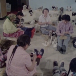 Still from "Mother of Many Children" featuring a group of older Inuit women sitting on the floor in a circle and weaving.