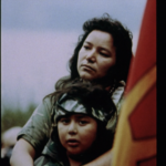 Still from the film "My Name is Kahenttiosta" featuring an image of Kahenttiosta and her son. and a Mohawk Warrior flag.