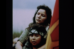 Still from the film "My Name is Kahenttiosta" featuring an image of Kahenttiosta and her son. and a Mohawk Warrior flag.