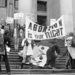 Black and white archival image of white women protestors on the steps of the Art Gallery in Vancouver holding various pro-choice banners.