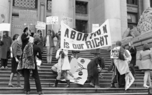 Black and white archival image of white women protestors on the steps of the Art Gallery in Vancouver holding various pro-choice banners.