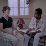 Still from "Sylvie's Story" depicting Sylvie, a white woman with short brown hair, speaking to a shelter worker, a black woman with short black hair.