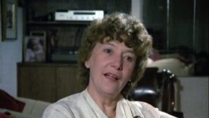 Still from the film "Love Affair with Politics" depicting Marion Dewar, a middle aged white woman with curly light brown hair, speaking to the camera.