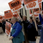 Still from the film "Why Women Run" depicting several elderly white women enthusiastically raising campaign signs that say "Elect Alexa McDonough NDP."