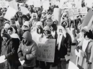 Still featuring a blurry black and white archival image of nurses striking.