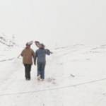 Still from the film "Moving Mountains" featuring two female miners holding shovels and walking in the snow.