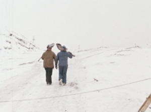 Still from the film "Moving Mountains" featuring two female miners holding shovels and walking in the snow.