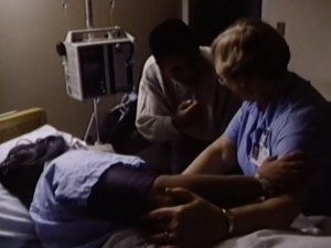 Still from the film "The Right to Care" featuring a nurse and a doctor treating a patient on a hospital bed.