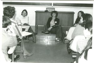 Group of women sitting in a classroom with notebooks.