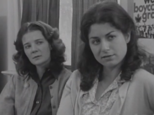 Black and white still from the film "Maria" featuring Maria and her mother talking to a union organizer.