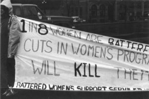 Photo of a banner highlighting violence against women and the impact of funding cuts to women's programs and services. It was part of the Banner Project, which asked women's groups across Canada to produce a protest banner that would become part of a huge banner in Ottawa. The goal was to show the strength and solidarity of women during the Third Commonwealth meeting of Ministers Responsible for Women’s Affairs in October 1990.