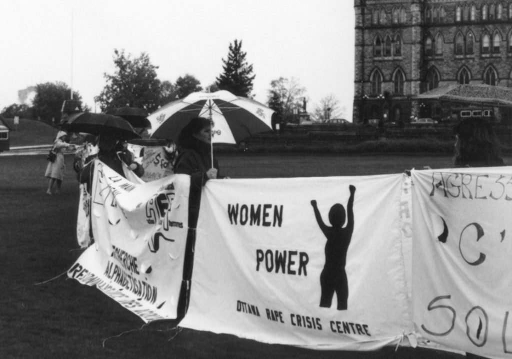 The theme of the Ottawa Rape Crisis Centre's banner is "Women Power." The Banner Project asked women's groups across Canada to produce a protest banner that would become part of a huge banner in Ottawa. The goal was to show the strength and solidarity of women during the Third Commonwealth meeting of Ministers Responsible for Women’s Affairs in October 1990.