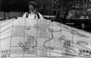 Photo from the Banner Project in 1990 showing B.C. Federation banner depicting the fight to end women's inequality as a Snakes and Ladders game. Women's groups across Canada were asked to produce a protest banner that would become part of a huge banner in Ottawa. The goal was to show the strength and solidarity of women during the Third Commonwealth meeting of Ministers Responsible for Women’s Affairs in October 1990.