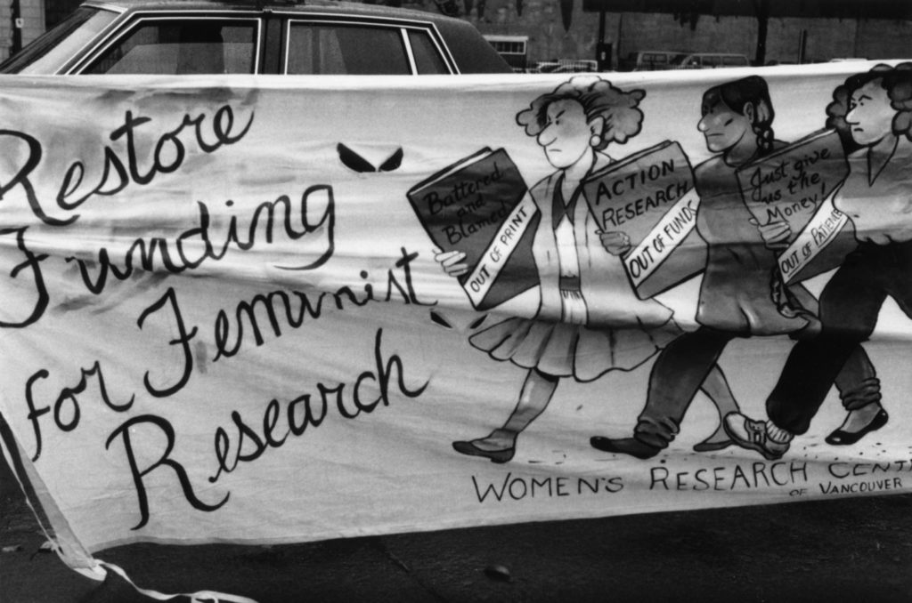 Photo of the Women's Research Centre of Vancouver banner which called for funding for feminist research to be restored. This banner was one of many created by women's groups across Canada that would become part of a huge banner in Ottawa. The goal was to show the strength and solidarity of women during the Third Commonwealth meeting of Ministers Responsible for Women’s Affairs in October 1990.