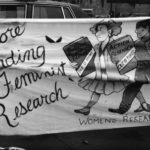 Photo of the Women's Research Centre of Vancouver banner which called for funding for feminist research to be restored. This banner was one of many created by women's groups across Canada that would become part of a huge banner in Ottawa. The goal was to show the strength and solidarity of women during the Third Commonwealth meeting of Ministers Responsible for Women’s Affairs in October 1990.