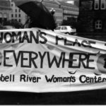 Photo of the Campbell River Woman's Center banner with the slogan "A Woman's Place is Everywhere". Women's groups across Canada were asked to produce a protest banner that would become part of a huge banner in Ottawa. The goal was to show the strength and solidarity of women during the Third Commonwealth meeting of Ministers Responsible for Women’s Affairs in October 1990.