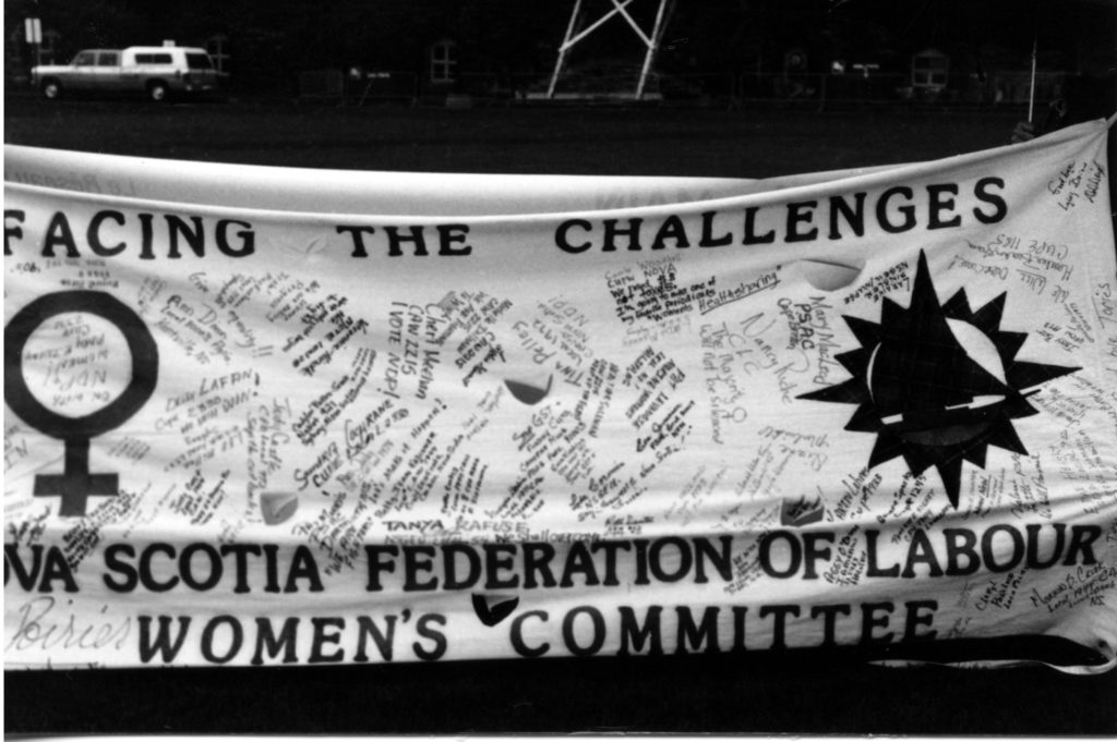 The Nova Scotia Federation of Labour Women's Committee banner was filled with dozens of signatures alongside the slogan "Facing the Challenges". It was part of The Banner Project which asked women's groups across Canada to produce a protest banner that would become part of a huge banner in Ottawa. The goal was to show the strength and solidarity of women during the Third Commonwealth meeting of Ministers Responsible for Women’s Affairs in October 1990.