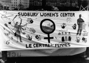 Photo of the Sudbury Women's Centre/Le centre des femmes section of the Banner Project. Women's groups across Canada were asked to produce a protest banner that would become part of a huge banner in Ottawa. The goal was to show the strength and solidarity of women during the Third Commonwealth meeting of Ministers Responsible for Women’s Affairs in October 1990.