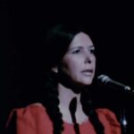 Image of a woman standing in front of a microphone while performing.