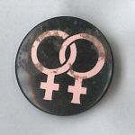 This is an undated button of two intertwined symbols of women.