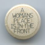 A button proclaiming that A Woman's Place is in the Front!