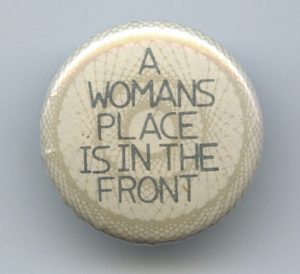 A button proclaiming that A Woman's Place is in the Front!