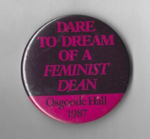 This button advocates for a feminist dean for Toronto's Osgoode Hall Law School in 1987.