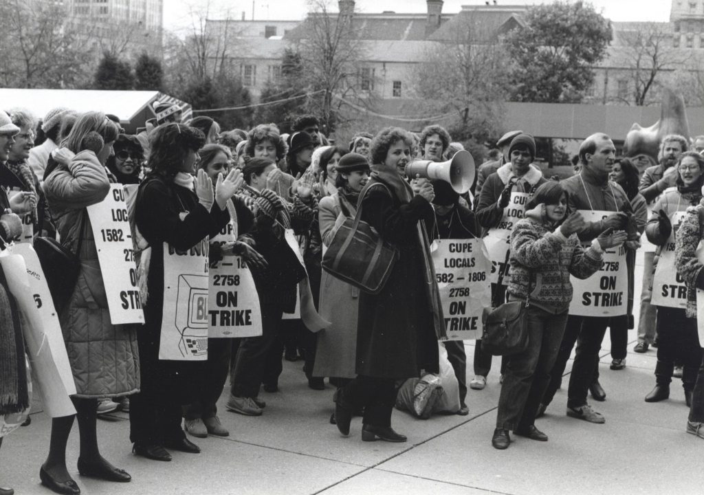 This is a photo of a rally at Toronto City Hall held by CUPE library workers who were on strike at the Metro Toronto Reference Library in 1984. Judy Darcy, head of the Strike Committee, is holding the megaphone.