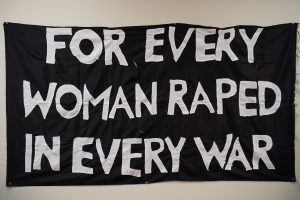 The banner For Every Woman Raped in Every War was produced by the Feminist Action Collective and used in an action with the poem of the same name on November 11, 1979, at the War Memorial on Wellington street, Ottawa. The banner was sewn at the Ottawa Women's Centre by a number of women who dropped in and picked up a threaded needle. - Wendy McPeake fonds 10-032, Canadian Women’s Archives, University of Ottawa Archives and Special Collections