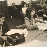 The photo shows an OFL presentation on equal pay to a Legislative Committee, Queens Park, Toronto, on January 30, 1980. (l to r: Mary Eady, Shelley Acheson, Cliff Pilkey). Audience members include Deirdre Gallagher, USW, behind Shelley; Edith Johnston, UAW; and Lena Kress, IBEW, in the next row.