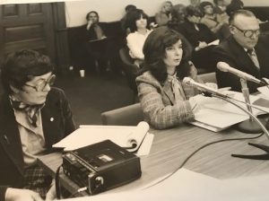 The photo shows an OFL presentation on equal pay to a Legislative Committee, Queens Park, Toronto, on January 30, 1980. (l to r: Mary Eady, Shelley Acheson, Cliff Pilkey). Audience members include Deirdre Gallagher, USW, behind Shelley; Edith Johnston, UAW; and Lena Kress, IBEW, in the next row.