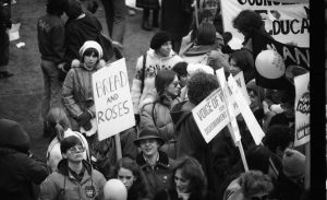 A woman at 1983 International Women's Day March in Toronto carries Bread and Roses sign.