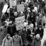 Placards at the 1983 International Women's Day March in Toronto call for universal day care and express solidarity with Central American and Caribbean countries, including El Salvador.