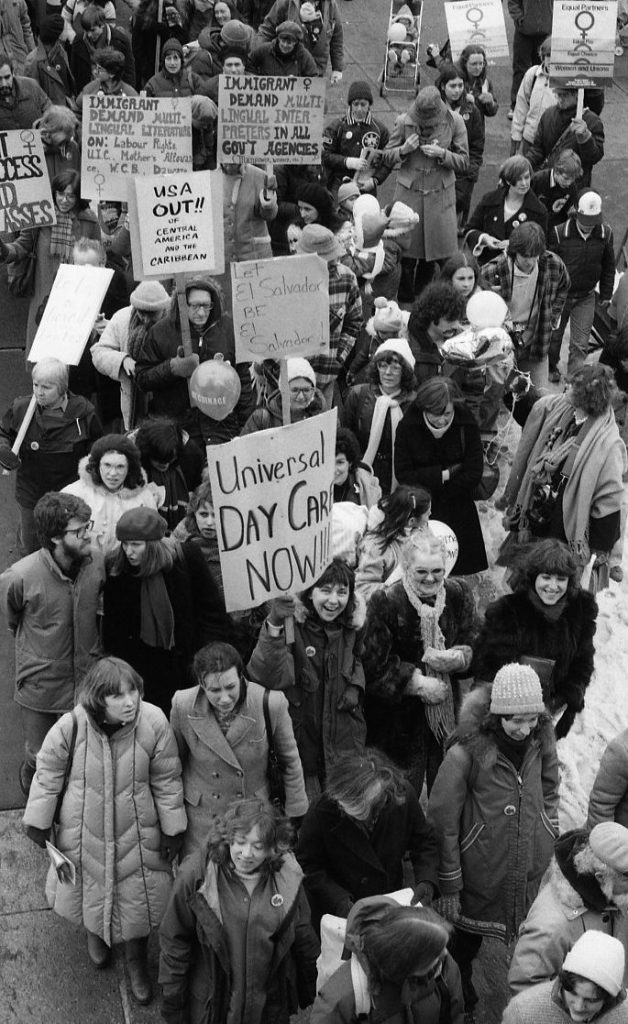 Placards at the 1983 International Women's Day March in Toronto call for universal day care and express solidarity with Central American and Caribbean countries, including El Salvador.