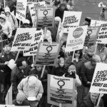 The Ontario Public Service Employees Union (OPSEU) contingent march at the 1983 International Women's Day March in Toronto carry placards carry calling for equal pay, paid maternity leave, ending sexual harassment, and social service cuts.