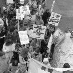 Members of the Ontario Public Service Employees Union (OPSEU) join the 1983 International Women's Day March in Toronto. Their placards highlight paid maternity leave, equal pay, and stopping sexual harassment, as well as the right to strike and social service cutbacks.