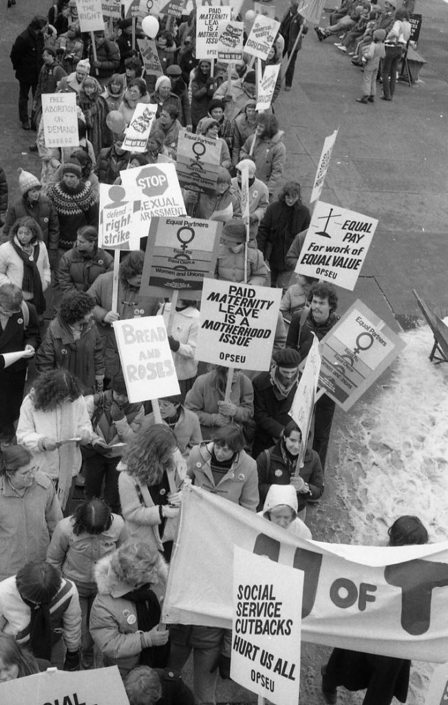 Members of the Ontario Public Service Employees Union (OPSEU) join the 1983 International Women's Day March in Toronto. Their placards highlight paid maternity leave, equal pay, and stopping sexual harassment, as well as the right to strike and social service cutbacks.