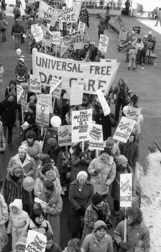 Action Daycare and other childcare activists join the 1983 International Women's Day March in Toronto. Signs call for universal quality daycare and paid maternity leave.