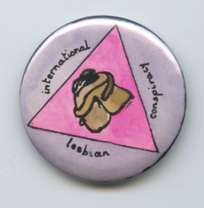 This undated button shows two women in a pink triangle embracing, together with the words "international lesbian conspiracy."