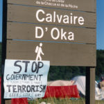 This photo is one of a number taken at the Oka Peace Camp set up in July 1990 in solidarity with the Mohawks of Kanehsatake who rose up in defense of their ancestral lands after the Oka Golf Club proposed an extension and the building of luxury condos over a Mohawk ancestral graveyard in the sacred wooded area known as “The Pines”. This land had never been ceded. In early July, after the Mohawks refused to end their non-violent occupation of the area or to take down the barricade, the Sûreté du Québec (Quebec police) moved in resulting in a violent confrontation. Later, the Canadian army was called in. Mohawk women, including Ellen Gabriel, played a central role in the uprising, which lasted for 78 intense days (July 11 – September 26, 1990). In the end, the golf course was not extended, and the condos were not built. But the larger issues of land sovereignty have never been resolved.