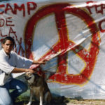 This photo is one of a number taken at the Oka Peace Camp set up in July 1990 in solidarity with the Mohawks of Kanehsatake who rose up in defense of their ancestral lands after the Oka Golf Club proposed an extension and the building of luxury condos over a Mohawk ancestral graveyard in the sacred wooded area known as “The Pines”. This land had never been ceded. In early July, after the Mohawks refused to end their non-violent occupation of the area or to take down the barricade, the Sûreté du Québec (Quebec police) moved in resulting in a violent confrontation. Later, the Canadian army was called in. Mohawk women, including Ellen Gabriel, played a central role in the uprising, which lasted for 78 intense days (July 11 – September 26, 1990). In the end, the golf course was not extended, and the condos were not built. But the larger issues of land sovereignty have never been resolved.