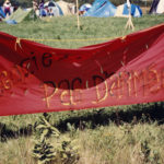 This photo is one of a number taken at the Oka Peace Camp set up in July 1990 in solidarity with the Mohawks of Kanehsatake who rose up in defense of their ancestral lands after the Oka Golf Club proposed an extension and the building of luxury condos over a Mohawk ancestral graveyard in the sacred wooded area known as “The Pines”. This land had never been ceded. In early July, after the Mohawks refused to end their non-violent occupation of the area or to take down the barricade, the Sûreté du Québec (Quebec police) moved in resulting in a violent confrontation. Later, the Canadian army was called in. Mohawk women, including Ellen Gabriel, played a central role in the uprising, which lasted for 78 intense days (July 11 – September 26, 1990). In the end, the golf course was not extended, and the condos were not built. But the larger issues of land sovereignty have never been resolved.