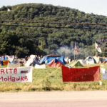 This photo is one of a number taken at the Oka Peace Camp set up in July 1990 in solidarity with the Mohawks of Kanehsatake who rose up in defense of their ancestral lands after the Oka Golf Club proposed an extension and the building of luxury condos over a Mohawk ancestral graveyard in the sacred wooded area known as “The Pines”. This land had never been ceded. In early July, after the Mohawks refused to end their non-violent occupation of the area or to take down the barricade, the Sûreté du Québec (Quebec police) moved in resulting in a violent confrontation. Later, the Canadian army was called in. Mohawk women, including Ellen Gabriel, played a central role in the uprising, which lasted for 78 intense days (July 11 – September 26, 1990). In the end, the golf course was not extended, and the condos were not built. But the larger issues of land sovereignty have never been resolved.