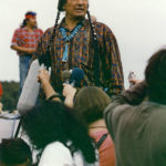 This photo is one of a number taken at the Oka Peace Camp set up in July 1990This photo is one of a number taken at the Oka Peace Camp set up in July 1990 in solidarity with the Mohawks of Kanehsatake who rose up in defense of their ancestral lands after the Oka Golf Club proposed an extension and the building of luxury condos over a Mohawk ancestral graveyard in the sacred wooded area known as “The Pines”. This land had never been ceded. In early July, after the Mohawks refused to end their non-violent occupation of the area or to take down the barricade, the Sûreté du Québec (Quebec police) moved in resulting in a violent confrontation. Later, the Canadian army was called in. Mohawk women, including Ellen Gabriel, played a central role in the uprising, which lasted for 78 intense days (July 11 – September 26, 1990). In the end, the golf course was not extended, and the condos were not built. But the larger issues of land sovereignty have never been resolved., in solidarity with the Mohawks of Kanehsatake who rose up in defense of their ancestral lands after the Oka Golf Course proposed an extension and the building of luxury condos over a Mohawk ancestral graveyard in the sacred wooded area known as “The Pines”. This land had never been ceded. In early July, after the Mohawks refused to end their non-violent occupation of the area or to take down the barricade, the Sûreté du Québec (Quebec police) moved in, resulting in a violent confrontation. Later, the Canadian army was called in. Mohawk women, including Ellen Gabriel, played a central role in the uprising, which lasted for 78 intense days (July 11 – September 26, 1990). In the end the golf course was not extended and the condos were not built. But the larger issues of land sovereignty have never been resolved.