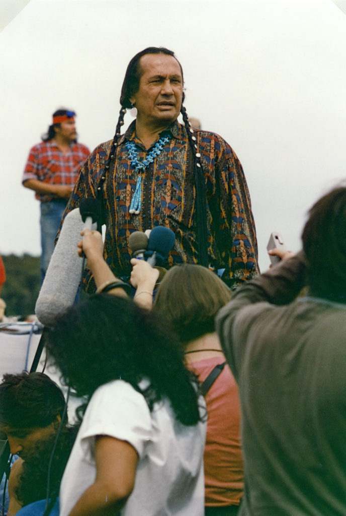 This photo is one of a number taken at the Oka Peace Camp set up in July 1990This photo is one of a number taken at the Oka Peace Camp set up in July 1990 in solidarity with the Mohawks of Kanehsatake who rose up in defense of their ancestral lands after the Oka Golf Club proposed an extension and the building of luxury condos over a Mohawk ancestral graveyard in the sacred wooded area known as “The Pines”. This land had never been ceded. In early July, after the Mohawks refused to end their non-violent occupation of the area or to take down the barricade, the Sûreté du Québec (Quebec police) moved in resulting in a violent confrontation. Later, the Canadian army was called in. Mohawk women, including Ellen Gabriel, played a central role in the uprising, which lasted for 78 intense days (July 11 – September 26, 1990). In the end, the golf course was not extended, and the condos were not built. But the larger issues of land sovereignty have never been resolved., in solidarity with the Mohawks of Kanehsatake who rose up in defense of their ancestral lands after the Oka Golf Course proposed an extension and the building of luxury condos over a Mohawk ancestral graveyard in the sacred wooded area known as “The Pines”. This land had never been ceded. In early July, after the Mohawks refused to end their non-violent occupation of the area or to take down the barricade, the Sûreté du Québec (Quebec police) moved in, resulting in a violent confrontation. Later, the Canadian army was called in. Mohawk women, including Ellen Gabriel, played a central role in the uprising, which lasted for 78 intense days (July 11 – September 26, 1990). In the end the golf course was not extended and the condos were not built. But the larger issues of land sovereignty have never been resolved.