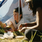 This photo is one of a number taken at the Oka Peace Camp set up in July 1990 in solidarity with the Mohawks of Kanehsatake who rose up in defense of their ancestral lands after the Oka Golf Club proposed an extension and the building of luxury condos over a Mohawk ancestral graveyard in the sacred wooded area known as “The Pines”. This land had never been ceded. In early July, after the Mohawks refused to end their non-violent occupation of the area or to take down the barricade, the Sûreté du Québec (Quebec police) moved in resulting in a violent confrontation. Later, the Canadian army was called in. Mohawk women, including Ellen Gabriel, played a central role in the uprising, which lasted for 78 intense days (July 11 – September 26, 1990). In the end, the golf course was not extended, and the condos were not built. But the larger issues of land sovereignty have never been resolved.