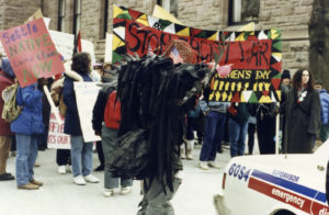 Marchers at the 1990 International Women's Day March in Toronto carry signs outside Queen's Park calling for settlement of Native Land claims and an end to the Gulf War.